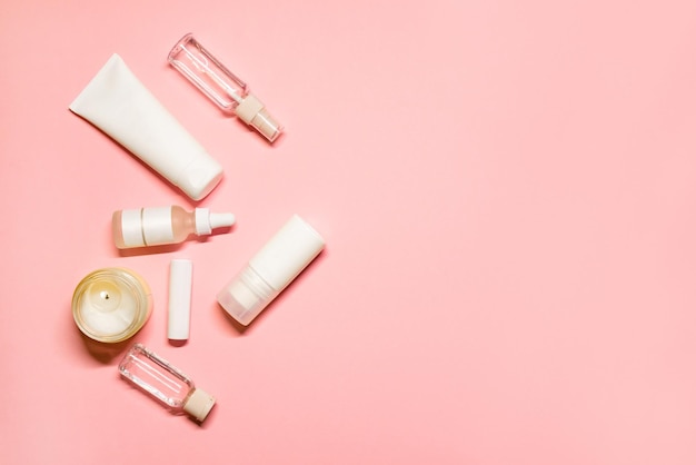 Flat lay shot with a copy space on a pink background with skincare goods hand cream deodorant