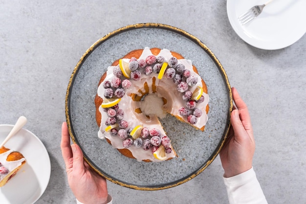 Disposizione piatta. fette di ciambella al limone e mirtilli rossi decorata con mirtilli rossi di zucchero e spicchi di limone su un supporto per torte.