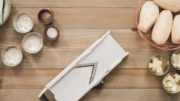 Flat lay. Slicing organic gold potatoes on a V-blade mandoline to prepare scalloped potatoes.