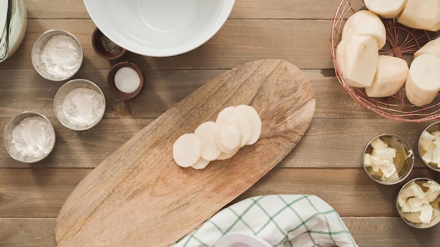 Flat lay. Slicing organic gold potatoes on a V-blade mandoline to prepare scalloped potatoes.