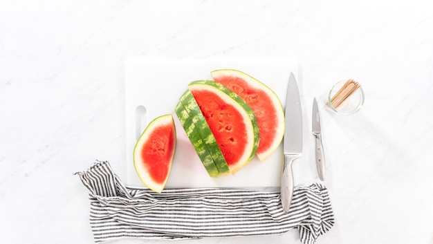 Flat lay. Slicing riped red watermelon to prepare chili lime watermelon pops.