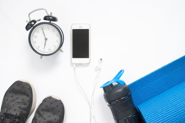 Flat lay of smartphone with alarm clock and sport yoga equipments on white background, Healthy lifestyle concept