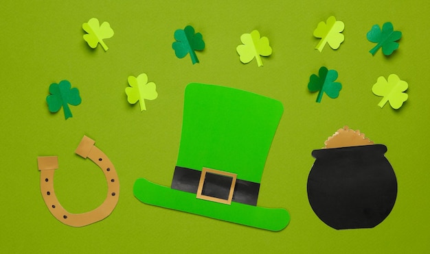 Flat lay st patricks dag stilleven klaver leprechaun hoed bowler hoed met goud en een hoefijzer op een groene achtergrond handgemaakte papierkunst
