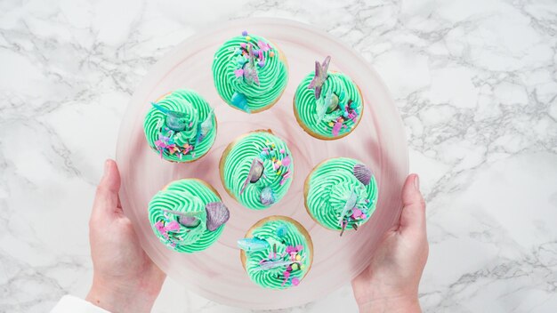 Photo flat lay. step by step. arranging mermaid vanilla cupcakes with chocolate mermaid tails on a cupcake stand.