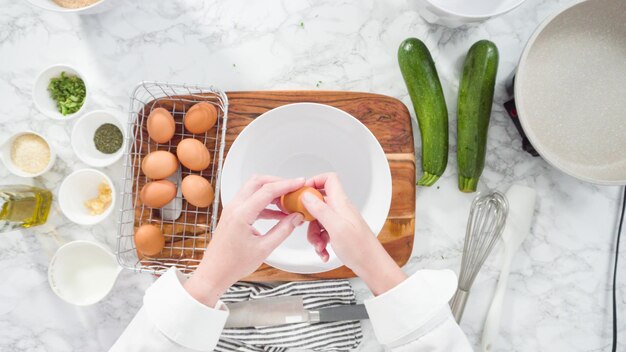 Flat lay. Step by step. Breaking organic brown eggs into the bowl to make zucchini cakes.