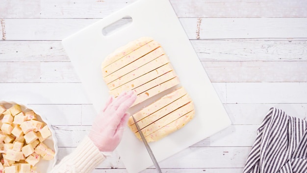 Flat lay. Step by step. Cutting homemade candy cane fudge on a white cutting board.