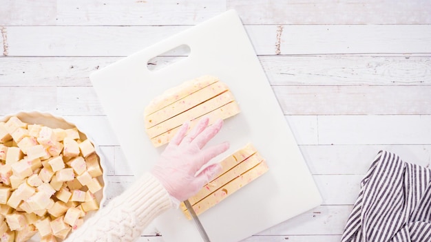 Flat lay. Step by step. Cutting homemade candy cane fudge on a white cutting board.