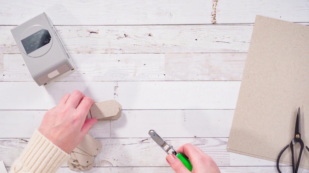 Flat lay. Step by step. Cutting out gift tags from brown paper with a paper punch.