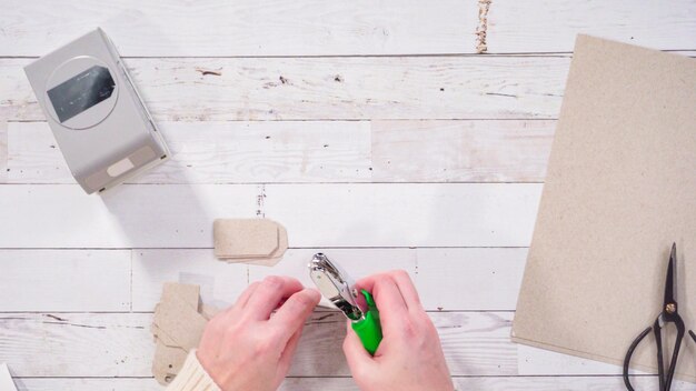 Photo flat lay. step by step. cutting out gift tags from brown paper with a paper punch.