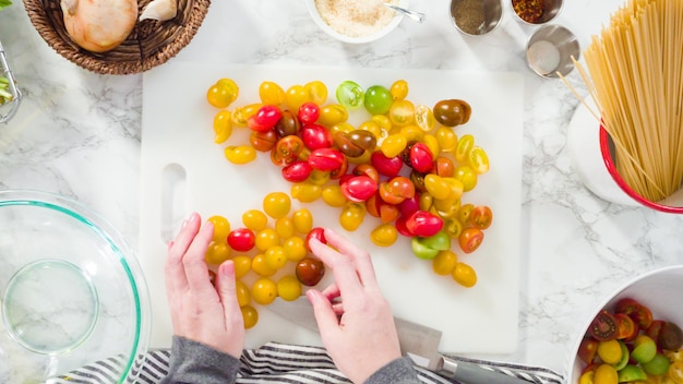 Flat lay. Step by step. Cutting vegetables on a white cutting board to make a one-pot pasta recipe.