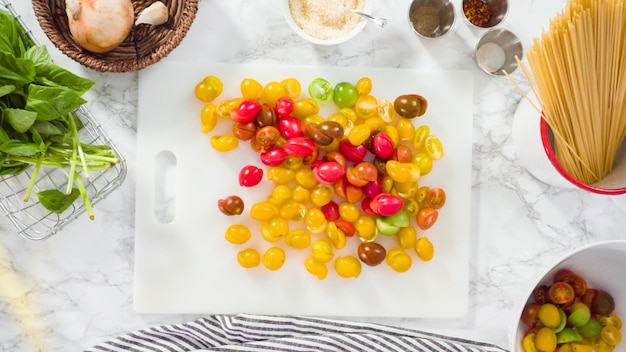 Flat lay. Step by step. Cutting vegetables on a white cutting board to make a one-pot pasta recipe.