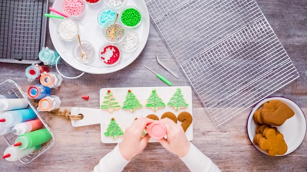 Disposizione piatta. passo dopo passo. decorare i biscotti di pan di zenzero e zucchero con la ghiaccia reale per natale.