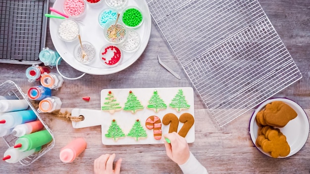 Disposizione piatta. passo dopo passo. decorare i biscotti di pan di zenzero e zucchero con la ghiaccia reale per natale.