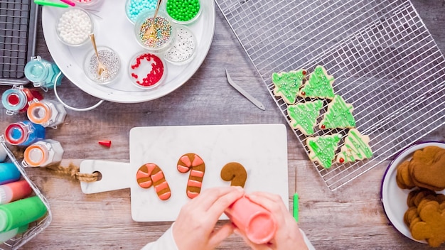 Disposizione piatta. passo dopo passo. decorare i biscotti di pan di zenzero e zucchero con la ghiaccia reale per natale.