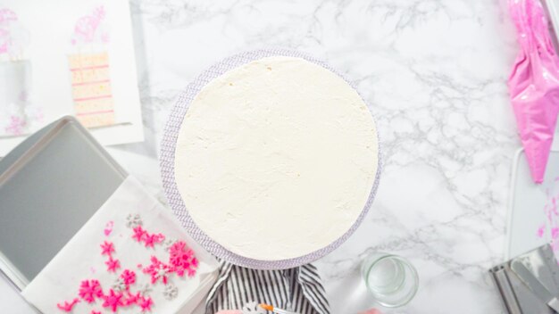 Flat lay. Step by step. Decorating round funfetti cake with pink and white fondant snowflakes.