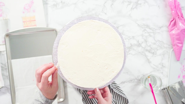 Flat lay. Step by step. Decorating round funfetti cake with pink and white fondant snowflakes.