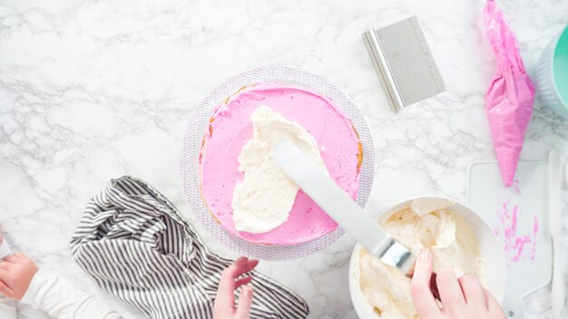 Flat lay. Step by step. Frosting round funfetti cake with white italian buttercream frosting.