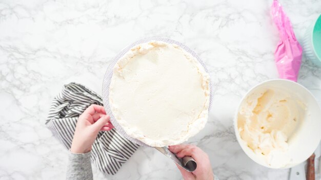 Flat lay. Step by step. Frosting round funfetti cake with white italian buttercream frosting.