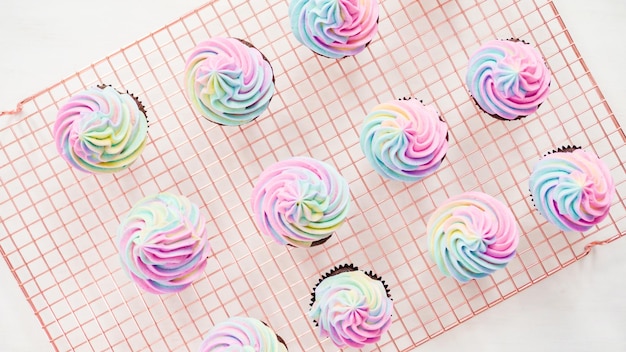 Flat lay. Step by step. Frosting unicorn chocolate cupcakes with rainbow color buttercream frosting.