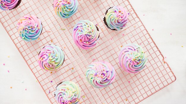 Flat lay. Step by step. Frosting unicorn chocolate cupcakes with rainbow color buttercream frosting.