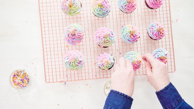 Flat lay. Step by step. Frosting unicorn chocolate cupcakes with rainbow color buttercream frosting.