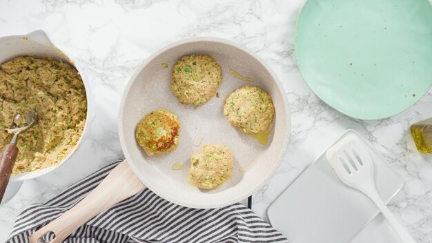 Flat lay. Step by step. Frying zucchini cakes in olive oil on a small frying pan.