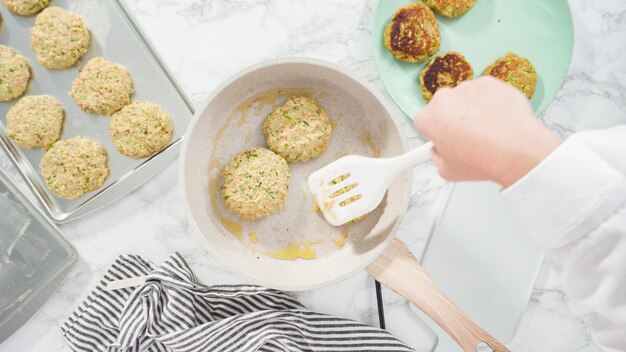 Flat lay. Step by step. Frying zucchini cakes in olive oil on a small frying pan.