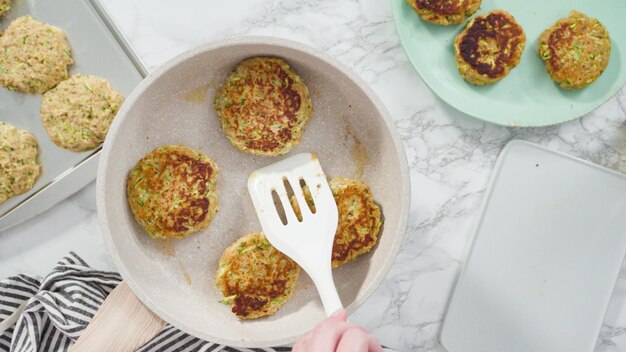 Flat lay. Step by step. Frying zucchini cakes in olive oil on a small frying pan.