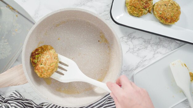 Flat lay. Step by step. Frying zucchini cakes in olive oil on a small frying pan.