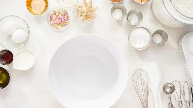 Flat lay. Step by step. Mixing ingredients together in a white mixing bowl to make unicorn chocolate cupcakes with buttercream frosting.