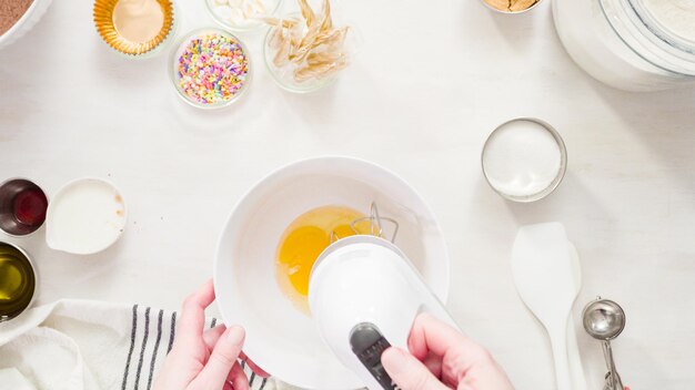 Flat lay. Step by step. Mixing ingredients together in a white mixing bowl to make unicorn chocolate cupcakes with buttercream frosting.