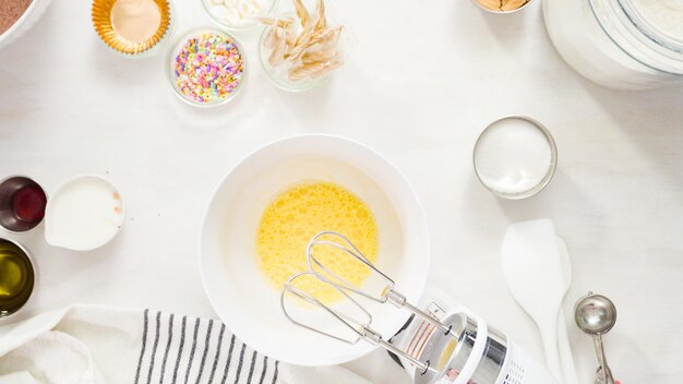 Flat lay. Step by step. Mixing ingredients together in a white mixing bowl to make unicorn chocolate cupcakes with buttercream frosting.