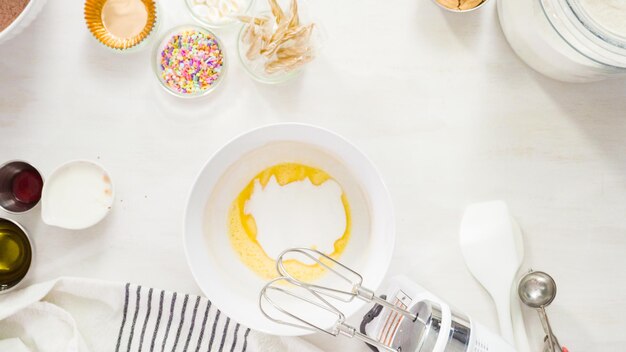 Flat lay. Step by step. Mixing ingredients together in a white mixing bowl to make unicorn chocolate cupcakes with buttercream frosting.