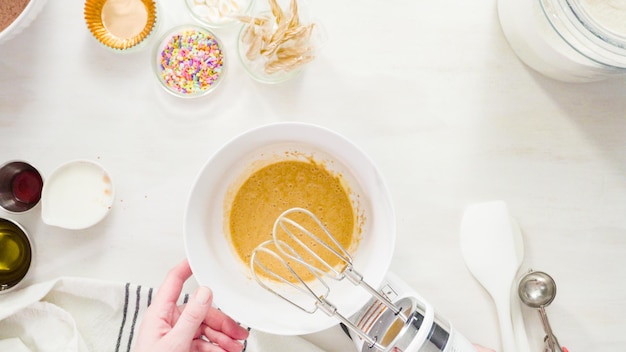 Flat lay. Step by step. Mixing ingredients together in a white mixing bowl to make unicorn chocolate cupcakes with buttercream frosting.