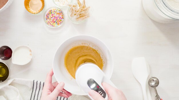 Flat lay. Step by step. Mixing ingredients together in a white mixing bowl to make unicorn chocolate cupcakes with buttercream frosting.