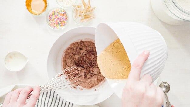 Flat lay. Step by step. Mixing ingredients together in a white mixing bowl to make unicorn chocolate cupcakes with buttercream frosting.