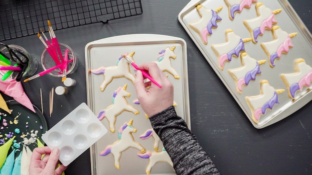 Flat lay. Step by step. Painting food glitter on top of unicorn sugar cookies with royal icing.