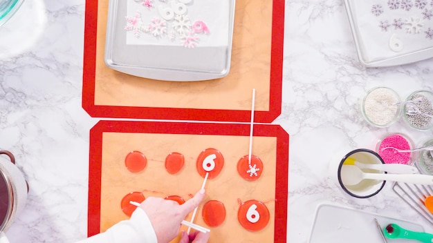 Flat lay. Step by step. Peeling cooled homemade lollipops from silicone baking mats.