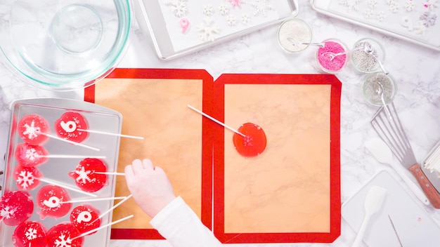 Flat lay. Step by step. Peeling cooled homemade lollipops from silicone baking mats.