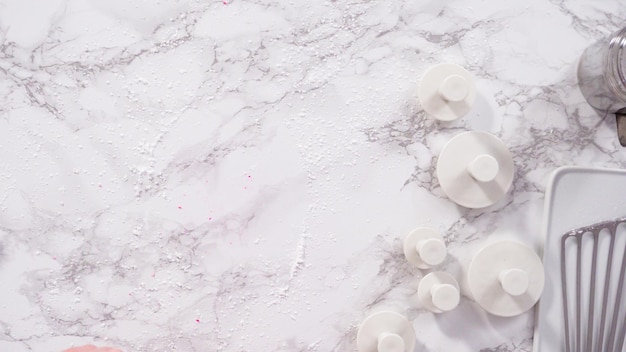 Flat lay. Step by step. Rolling our pink fondant on a marble counter.