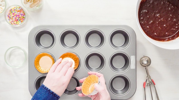 Photo flat lay. step by step. scooping batter with a cupcake scoop to make unicorn chocolate cupcakes with buttercream frosting.