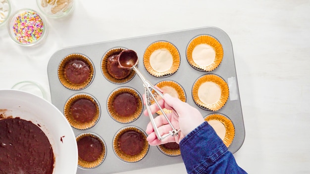 Flat lay. Step by step. Scooping batter with a cupcake scoop to make unicorn chocolate cupcakes with buttercream frosting.