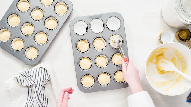 Photo flat lay. step by step. scooping cupcake batter into cupcake liners to bake vanilla cupcakes.
