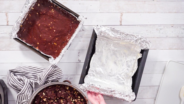 Flat lay. Step by step. Scooping melted chocolate into baking pans lined with cooking foil to make macadamia nut fudge.