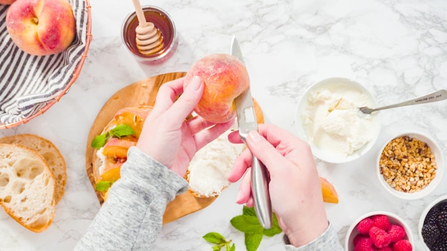 Flat lay. Step by step. Slicing organic peach to make a ricotta and peach toast on ciabatta bread.