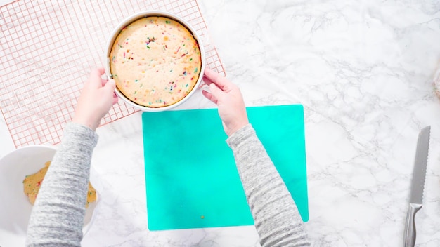 Flat lay. Step by step. Wrapping freshly baked funfetti cake into cellophane and cooking foil for freezer storage.