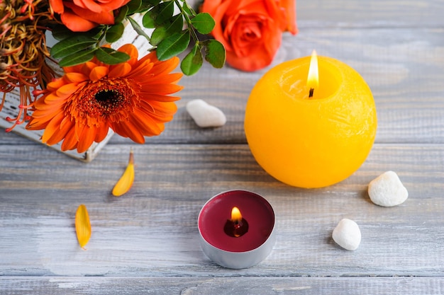 Flat lay still life with orange flowers lit candles and pebbles