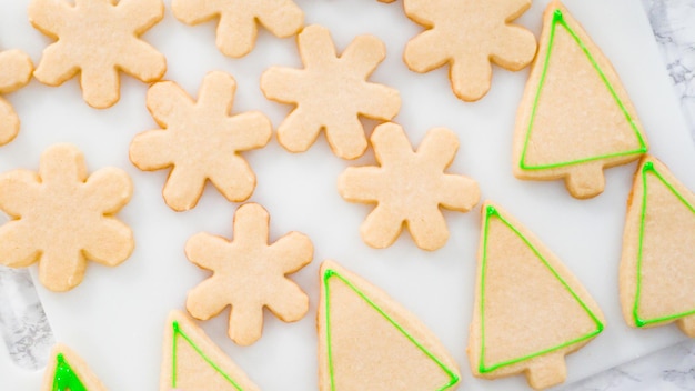 Flat lay. Stp by step. Icing Christmas tree-shaped sugar cookies with green royal icing.