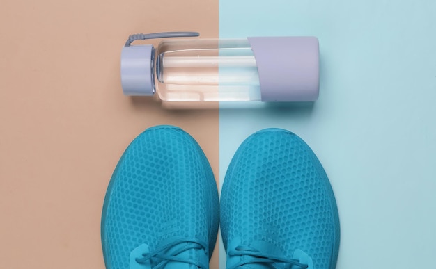 Flat lay style concept of healthy lifestyle sport and fitness Sports shoes for running  bottle of water on pink blue pastel background Top view