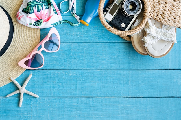 Flat lay of summer accessories with bikini on blue wooden background